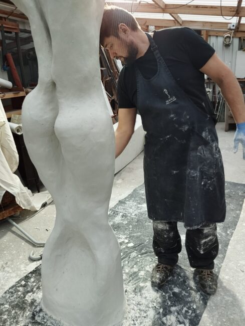 Valeriu Cazacevschi working in his studio, shaping a tall white sculpture